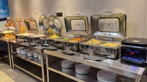 A buffet setup with various food items and serving utensils.