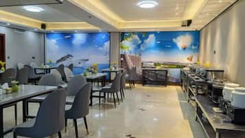 A dining area with tables and chairs, a buffet setup, and a mural with a landscape and clouds.