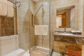 A modern bathroom with a glass shower enclosure, a marble countertop, and a visible toilet. - Wanhao Holiday Hotel (Dao County)