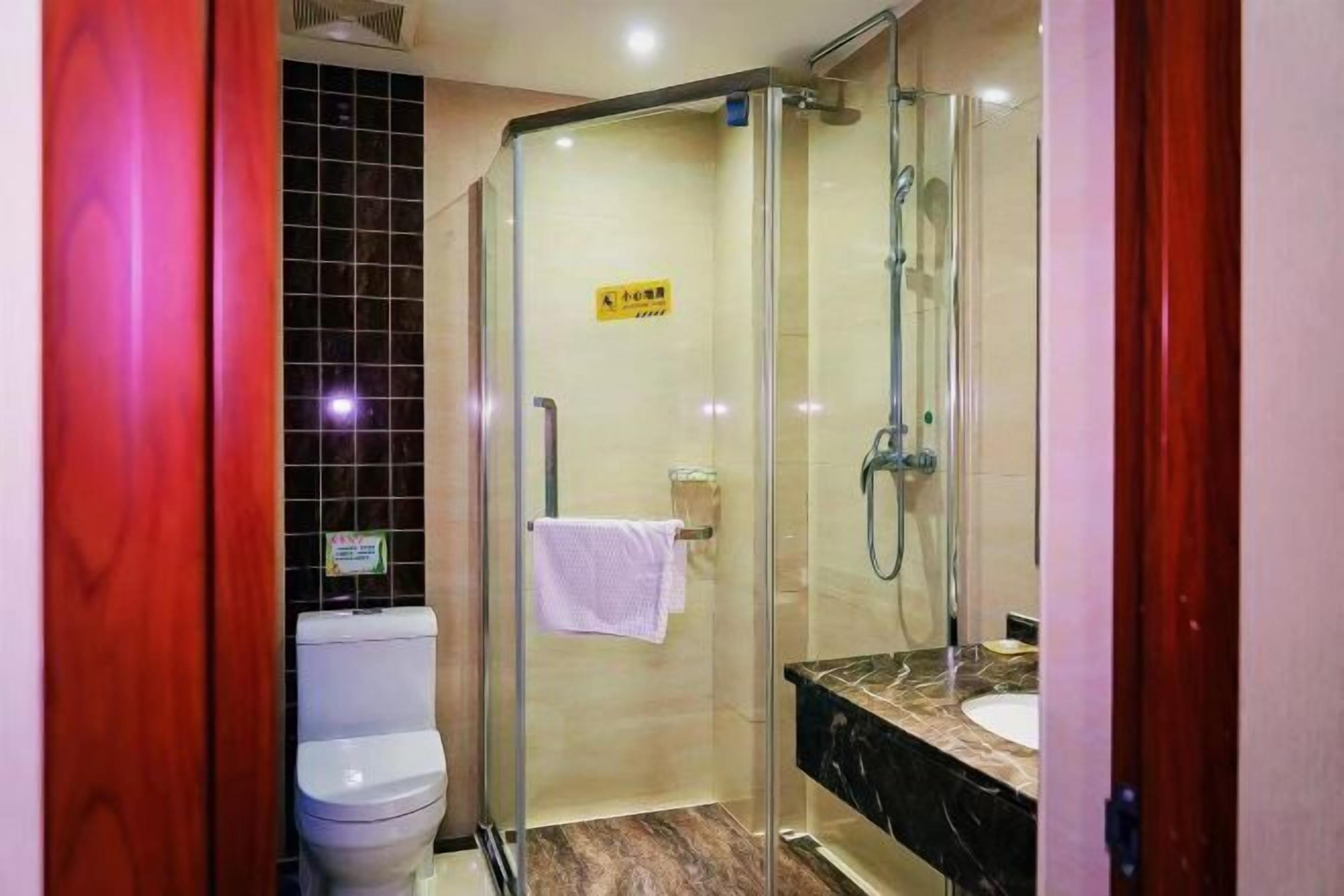 A bathroom with a glass-enclosed shower, a toilet, a sink, and a mirror.