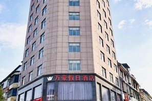 A hotel with a modern facade, featuring a prominent signage in a foreign language. - Wanhao Holiday Hotel (Dao County)