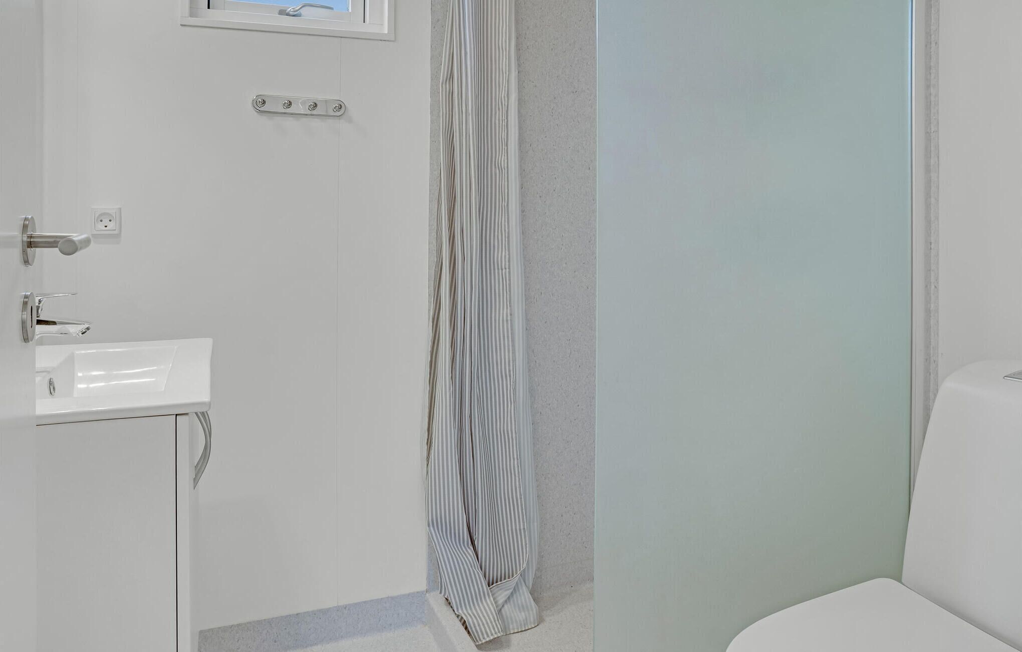A bathroom with a white sink, a shower curtain, and a toilet.