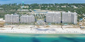 Resort costeiro com três edifícios altos, praia e um reservatório de água.