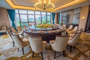 Uma sala de conferências com uma mesa redonda, cadeiras e um candelabro.