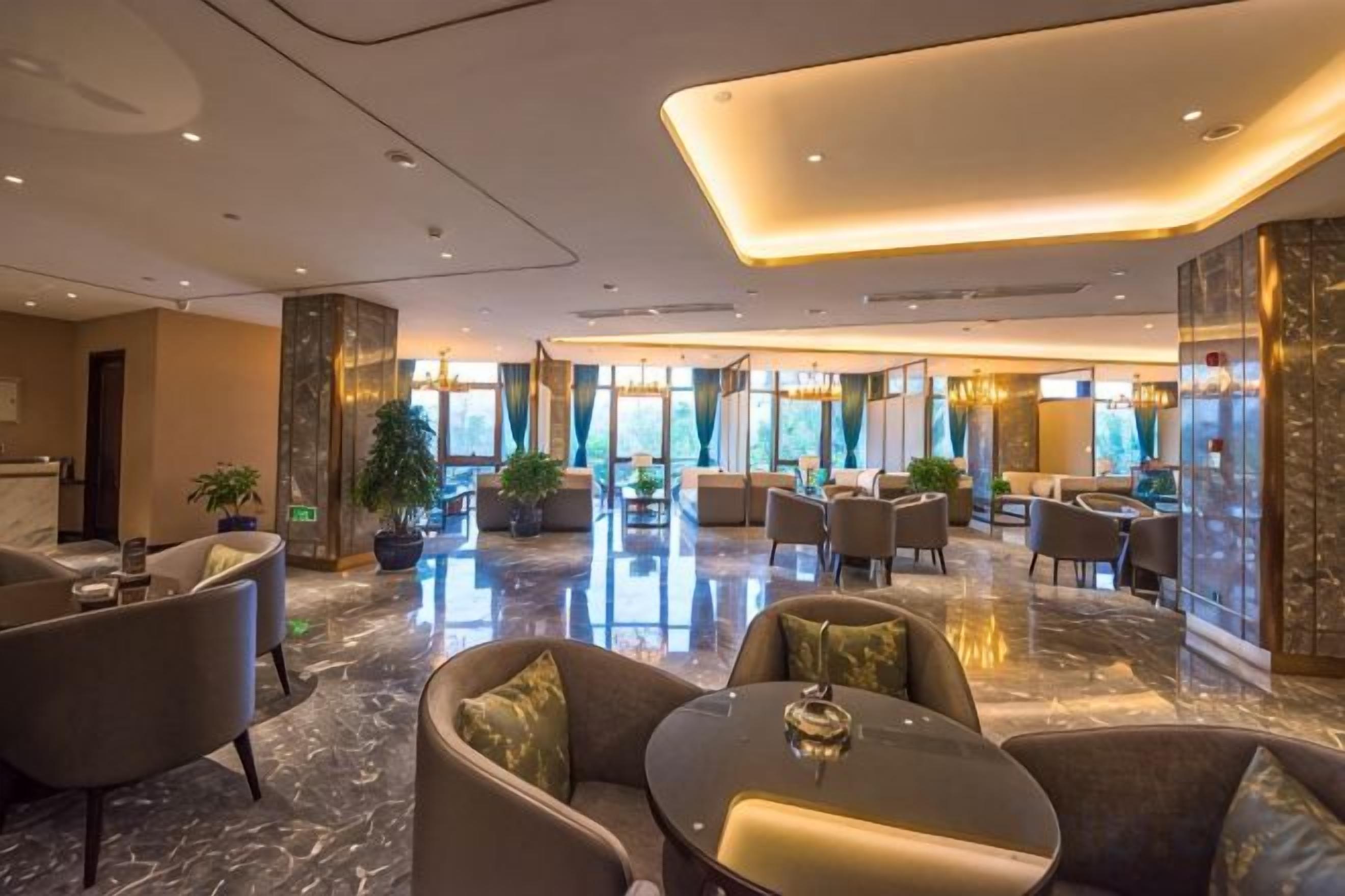 A hotel lobby with a marble floor, seating areas, and large windows.