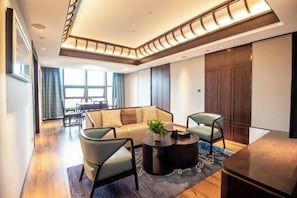 A modern living room with a sofa, two armchairs, a coffee table, and a dining area in the background. - Jinyang Shangcheng Hotel (Jintang)