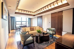 Una sala de estar moderna con un sofá, dos sillones, una mesa de centro y un área de comedor al fondo.