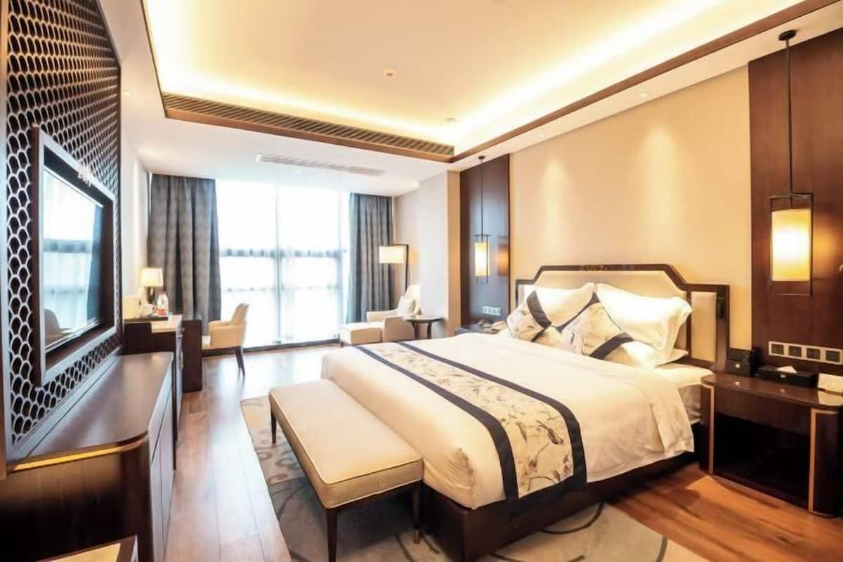 A modern hotel room with a large bed, a desk, and a seating area.