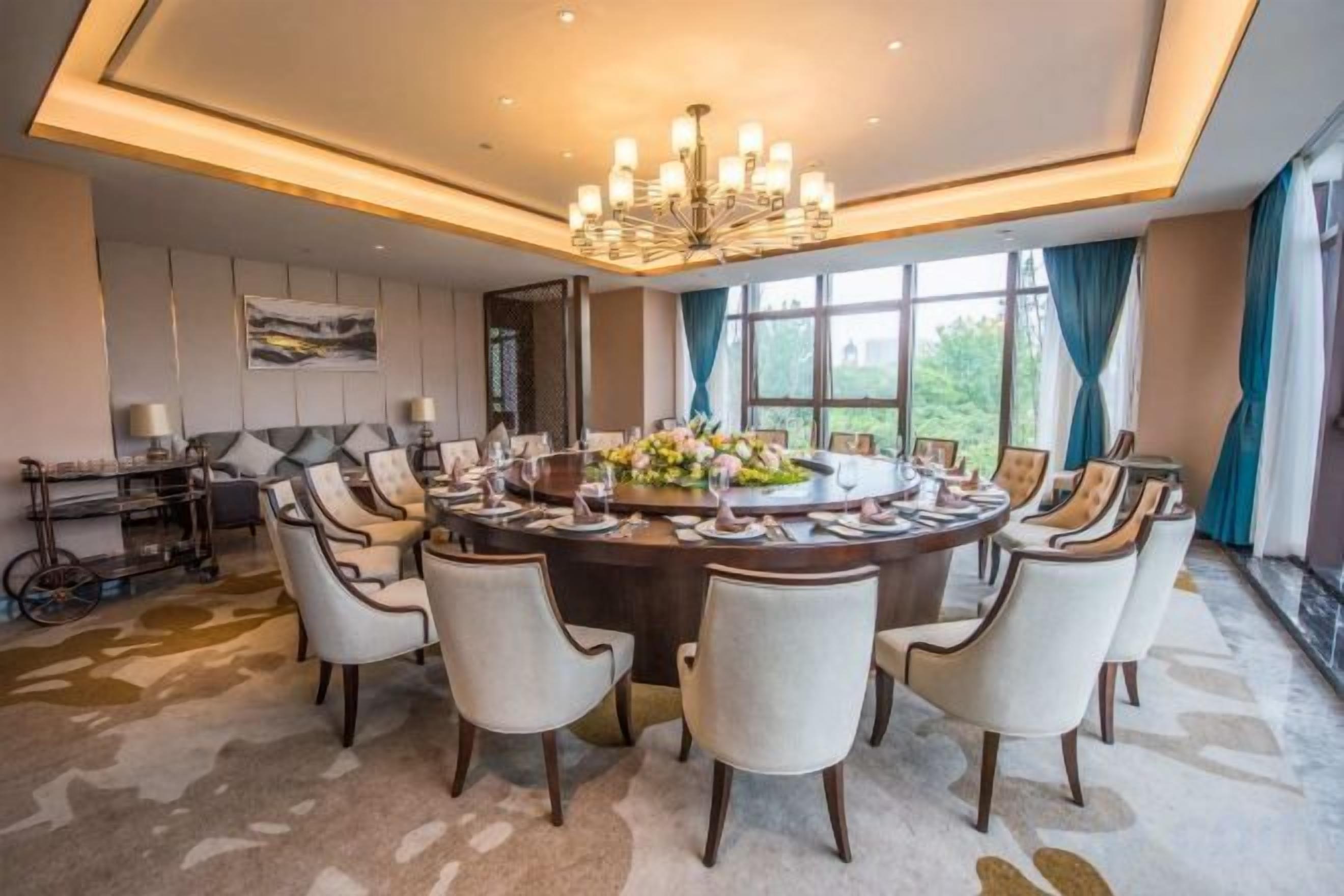 A formal dining room with a round table, multiple chairs, and a chandelier.