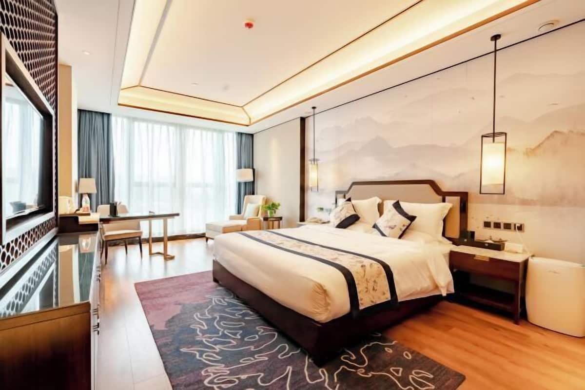 A modern hotel room with a large bed, bedside tables, a desk, and a TV.