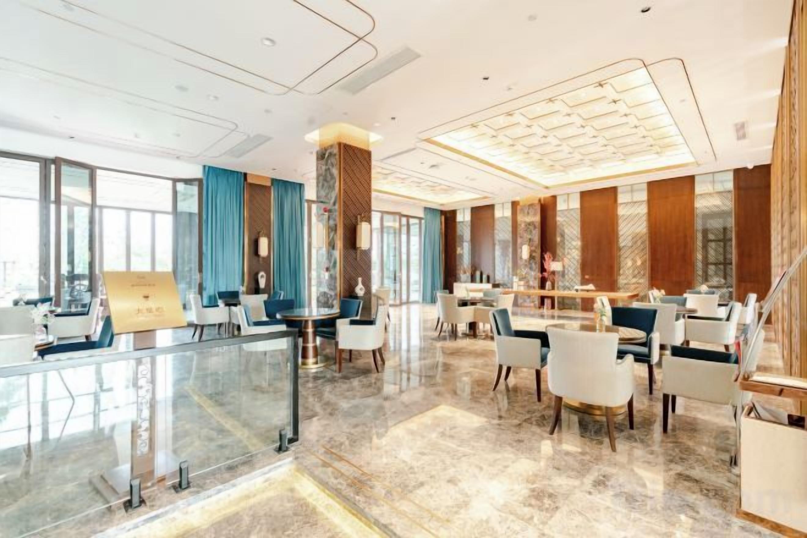 A modern hotel lobby with a glass partition, seating areas, and a reception desk.