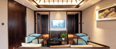 A modern living room with a sofa, two armchairs, a coffee table, and a TV on the wall.