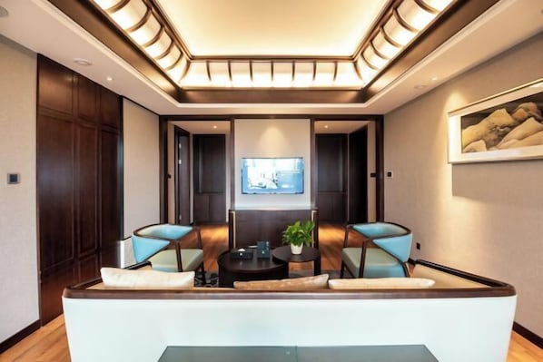 A modern living room with a sofa, two armchairs, a coffee table, and a TV on the wall. - Jinyang Shangcheng Hotel (Jintang)
