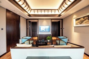 Una sala de estar moderna con un sofá, dos sillones, una mesa de centro y un televisor en la pared.