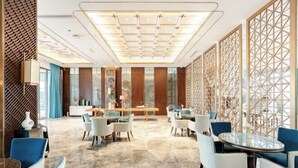 A spacious lobby with a central seating area, a patterned wall, and a decorative ceiling. - Jinyang Shangcheng Hotel (Jintang)