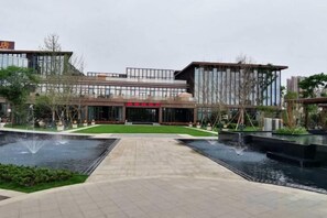 Un edificio moderno con un patio central, una fuente de agua y un césped bien cuidado.