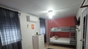 A bedroom with a single bed, a desk, a dresser, a bunk bed, and a ceiling fan. - Apt w/ Pool Deck & Games, 5 mins From The Beach- CU (Isabela)