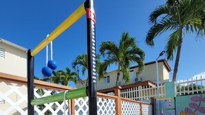 A wooden deck with a playground structure featuring a black pole, yellow and green bars, and blue balls. - Apt w/ Pool Deck & Games, 5 mins From The Beach- CU (Isabela)