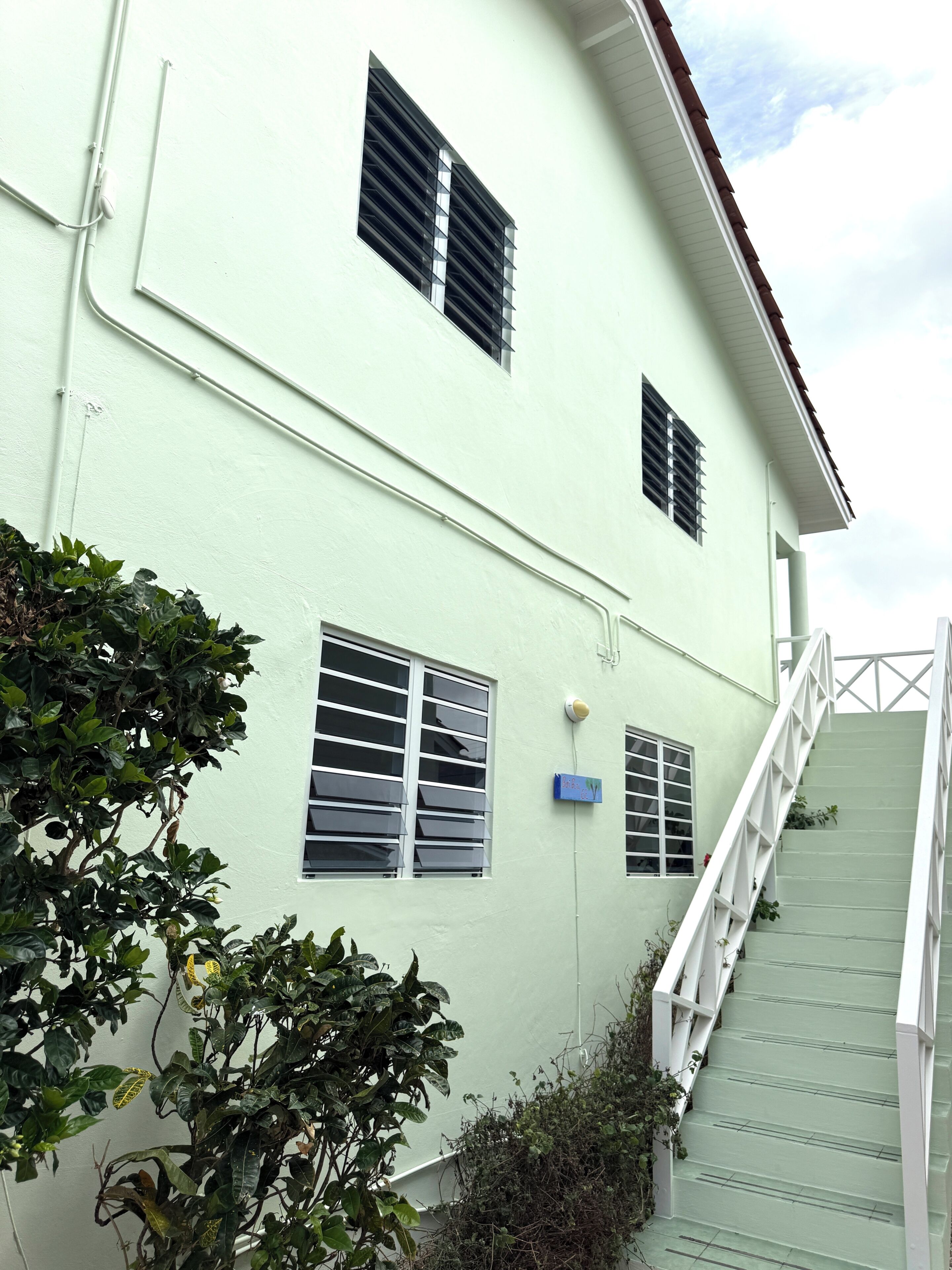 A building with multiple windows, a staircase, and some greenery.
