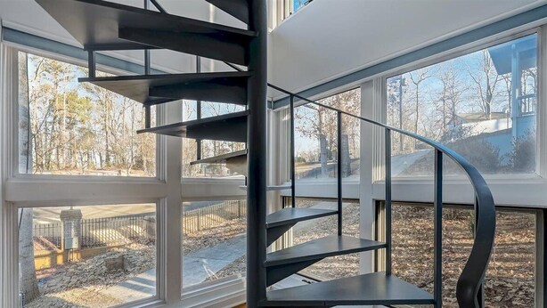 A modern spiral staircase with a metal finish, leading to an upper floor.