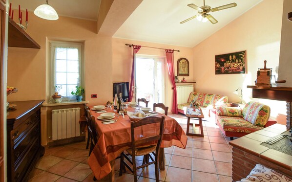 Un coin repas avec une table dressée pour quatre personnes, un canapé, un téléviseur et un ventilateur de plafond.