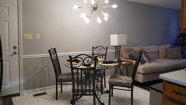 A dining area with a table and chairs, a chandelier, a sofa, and a Christmas tree. - Cozy House Close To Everything Anderson Has To Offer (Anderson)