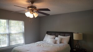 A bedroom with a bed, a nightstand, a lamp, and a ceiling fan. - Cozy House Close To Everything Anderson Has To Offer (Anderson)