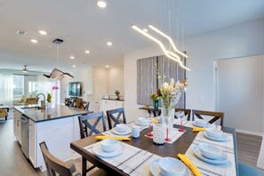 A modern dining area with a central island, white plates, and a vase with flowers. - Durham Vacation Rental w/ Community Pools! (Durham)