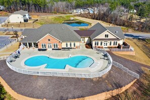 A large, circular swimming pool with a unique design, surrounded by a covered patio area with seating. - Durham Vacation Rental w/ Community Pools! (Durham)