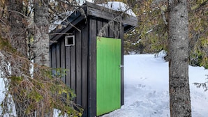 A wooden cabin with a green door, surrounded by trees and snow. - Cozy home in Vinstra with kitchen (Vinstra)