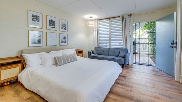 Un dormitorio con una cama grande, un sofá gris y cuadros enmarcados en la pared.