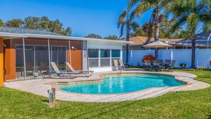 A backyard with a swimming pool, lounge chairs, and a patio area. - My Happy Place – Heated Pool, Dual Living Rooms, Screened Lanai & Nearby Indian Rocks Beach (Seminole)