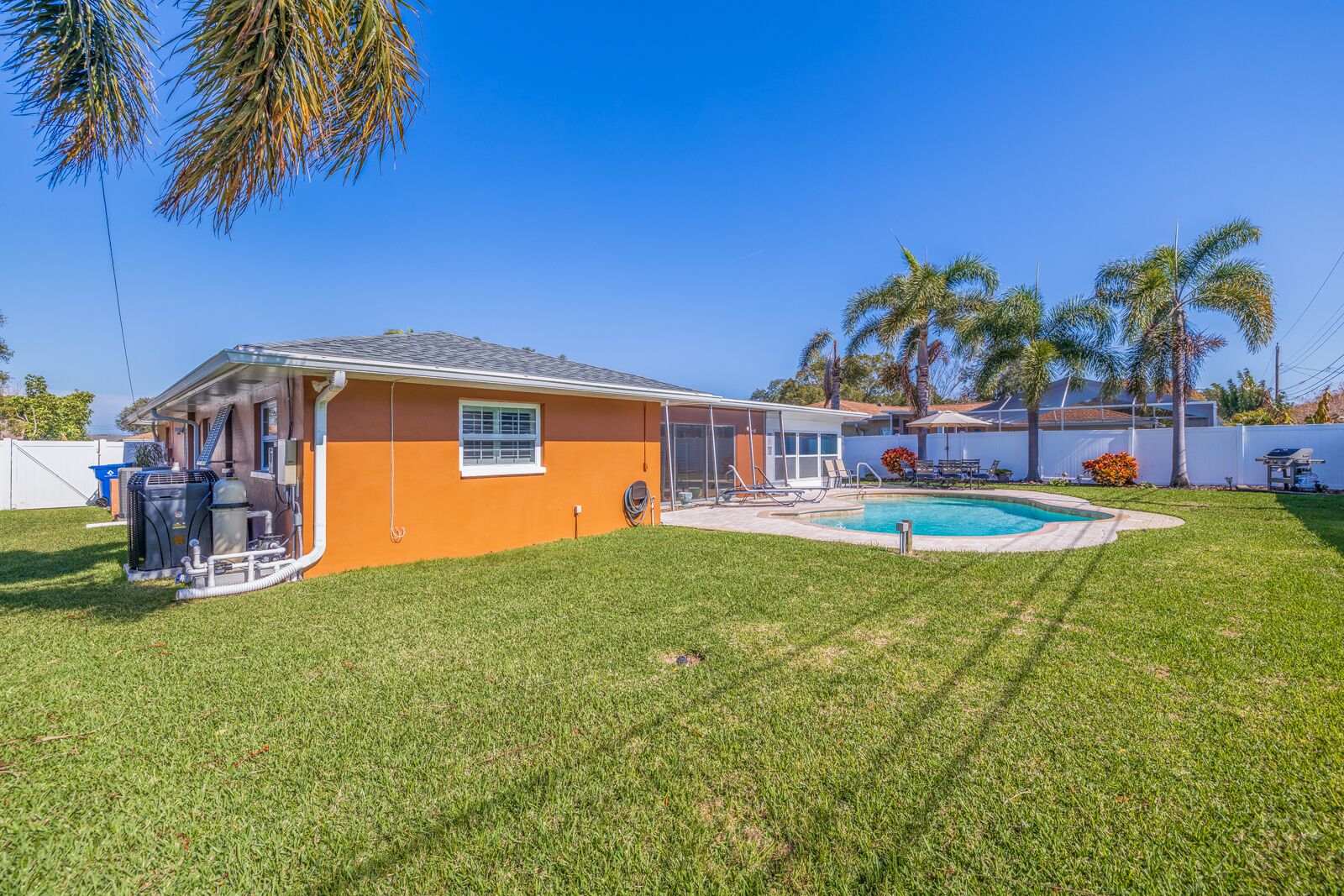 Ein Wohnhaus mit Schwimmbad, überdachter Terrasse und Rasenfläche.