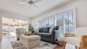 A spacious living room with a grey sofa, a white armchair, and a wooden coffee table. - My Happy Place – Heated Pool, Dual Living Rooms, Screened Lanai & Nearby Indian Rocks Beach (Seminole)