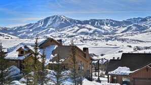 Un paysage montagneux enneigé, avec une zone résidentielle comprenant des maisons en bois aux toits inclinés, sous un ciel dégagé.