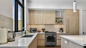 Une cuisine moderne avec des meubles en bois, une cuisinière en acier inoxydable et un four encastré.