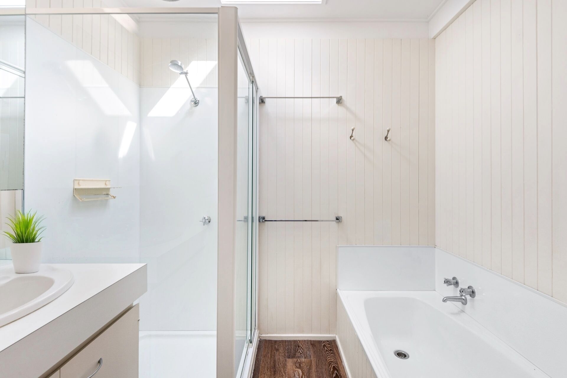 A modern bathroom with a glass-enclosed shower, a freestanding bathtub, and a vanity with a sink and mirror.