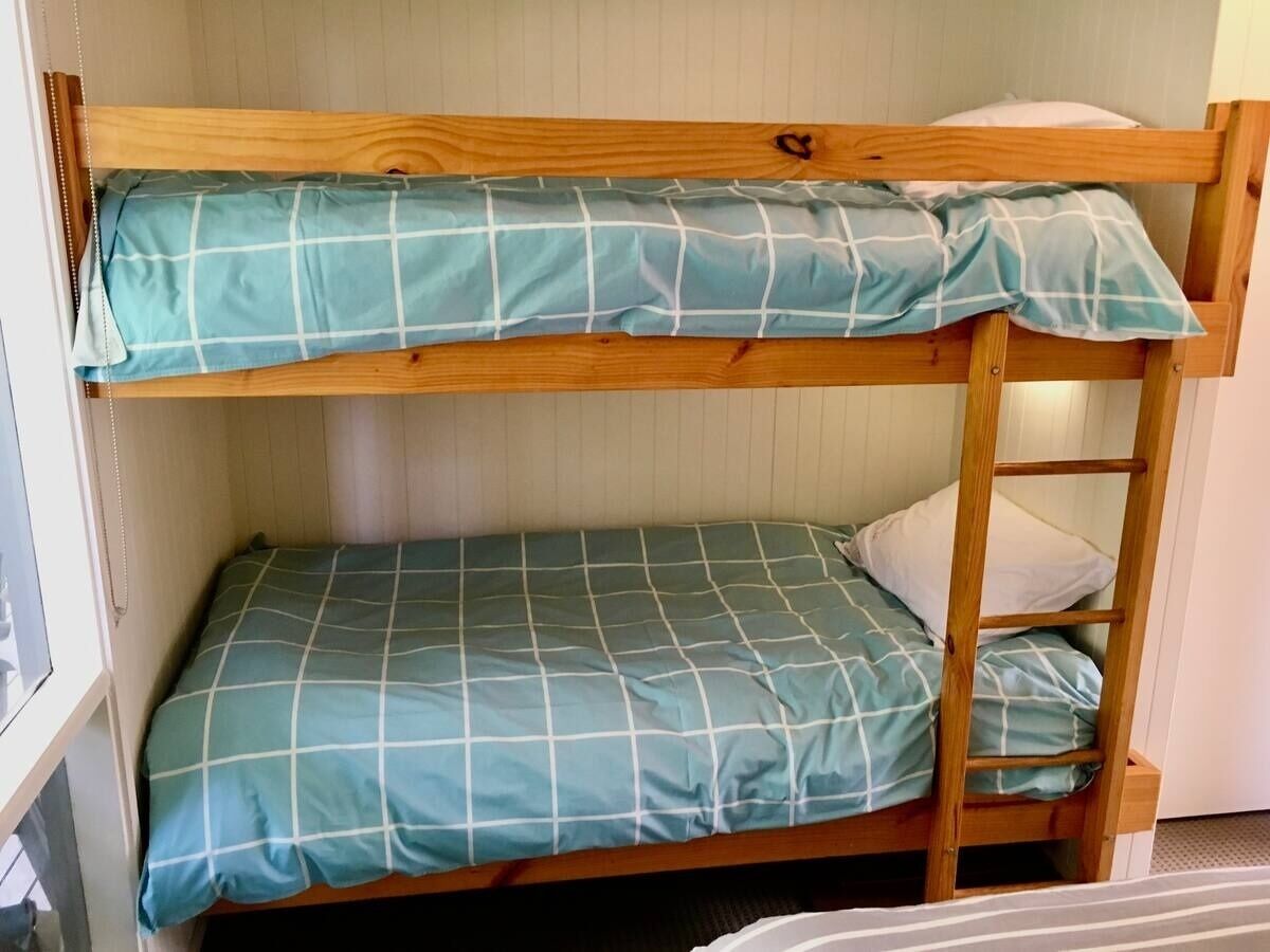 Un letto a castello con struttura in legno e copriletto a quadri blu.
