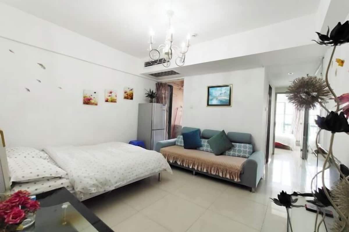 Une chambre à coucher moderne avec un lit, un canapé et des plantes décoratives.