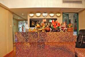 A reception desk with a tiled barrier, a clock, and a wall-mounted display of various statues. - Jufuyuan Apartment (Shenzhen)