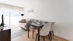 Una sala de estar moderna con comedor, que incluye un sofá, una mesa de centro y una mesa de comedor con platos y vasos.