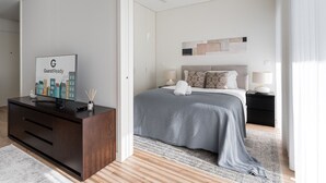 Una habitación de hotel moderna con una cama, mesitas de noche, un escritorio con computadora y vistas a la ciudad.