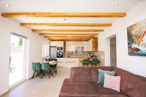 Ein modernes Interieur mit Essbereich, Küche und einem braunen Sofa mit Kissen.