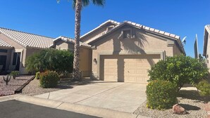 A residential house with a tiled roof, a garage, and a palm tree in the front yard. - Private Pool on the Golf Course in Surprise (Surprise)