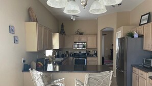 A modern kitchen with a central island, stainless steel appliances, and light-colored cabinetry. - Private Pool on the Golf Course in Surprise (Surprise)