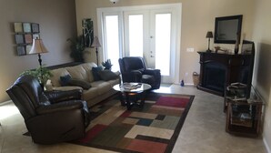A living room with a sofa, two armchairs, a coffee table, a fireplace, and a television. - Private Pool on the Golf Course in Surprise (Surprise)