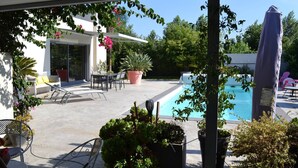 Une terrasse extérieure moderne avec une piscine, des coins salon et des plantes en pot.