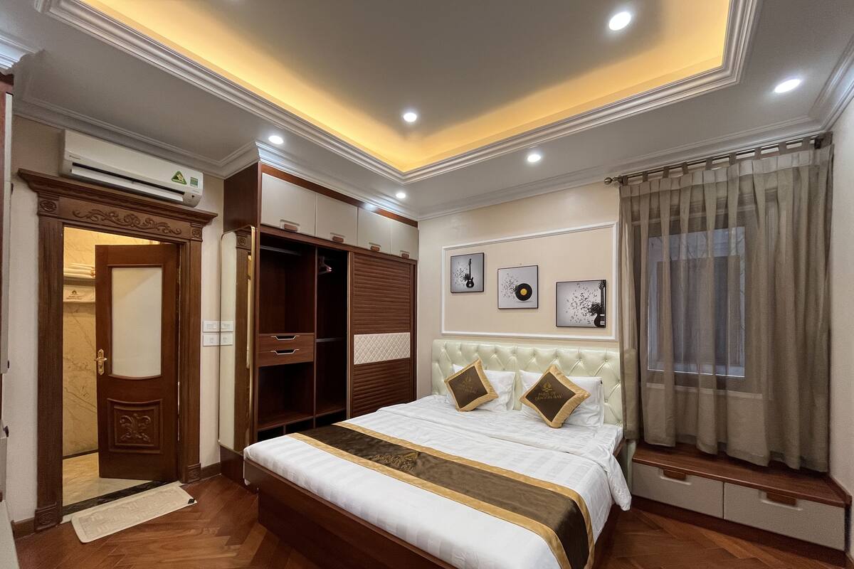 A hotel room with a large bed, built-in wardrobe, and a ceiling with recessed lighting.