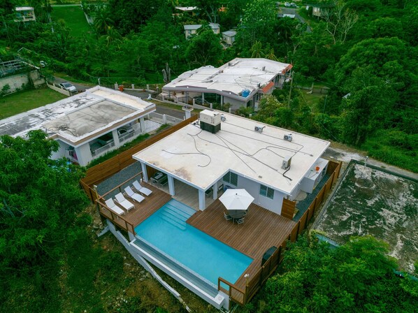 A modern house with a rooftop pool, a large deck, and a spacious backyard.