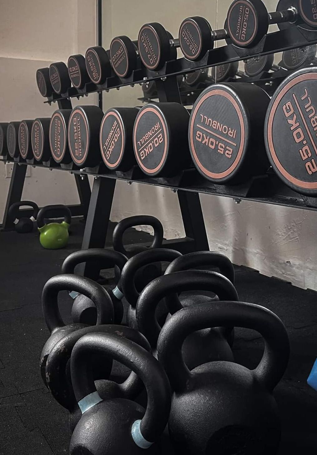 A weightlifting area with dumbbells and kettlebells.